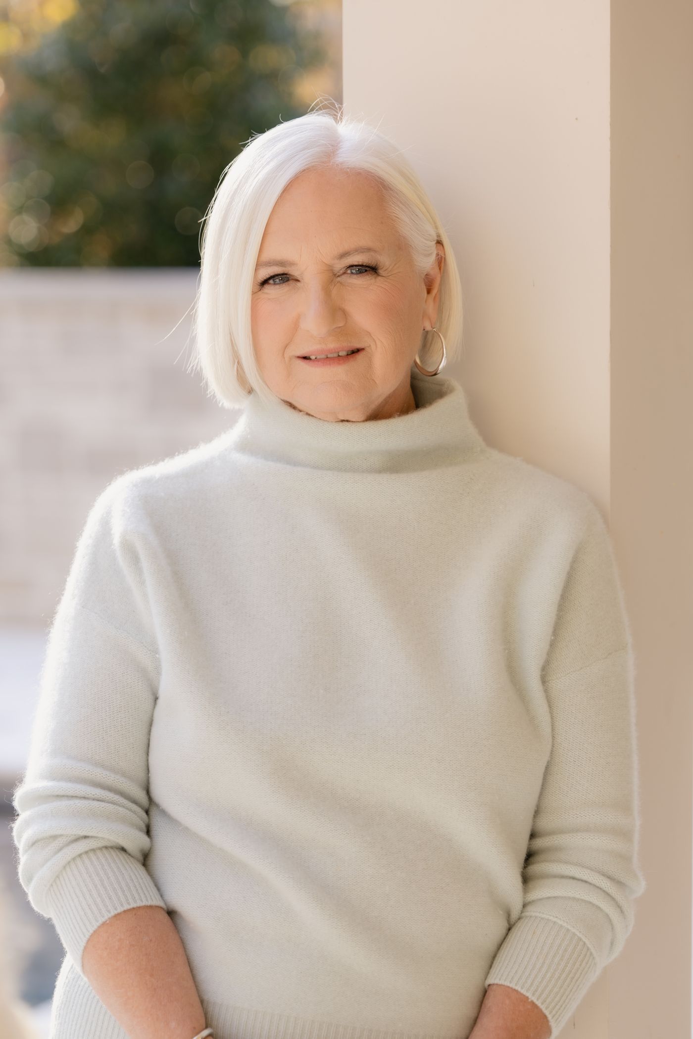 Catherine Taylor Hickem smiling, leaning against a porch column